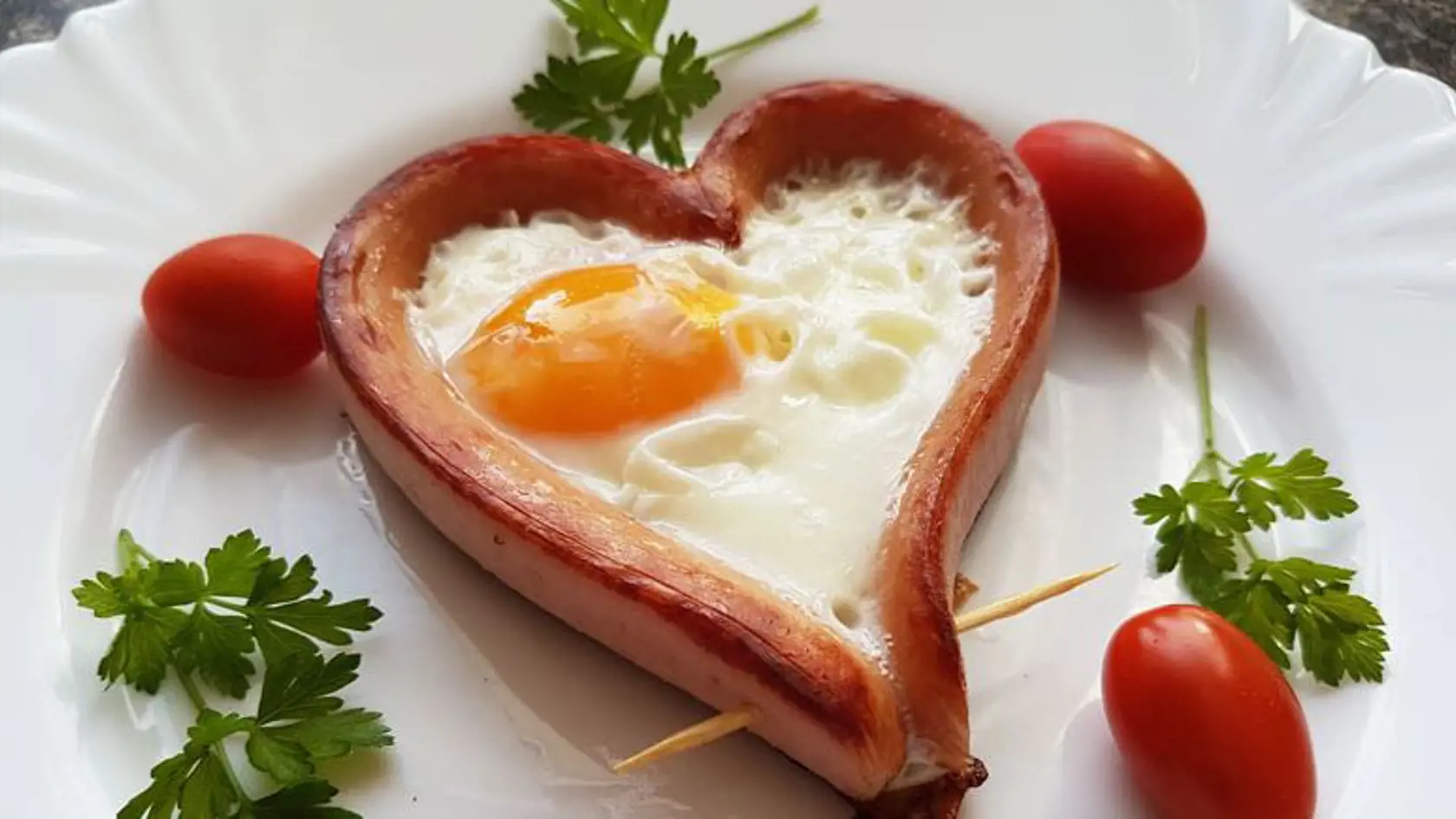 VALENTÍNSKE RANAJKY od Jozefíny zo Šenkvíc: Raňajkové párkové srdiečko Potrebujeme: 
párky, vajíčka, olej, zelenina na ozdobu
Postup: Párky pozdĺžne prekrojíme tak, aby jeden koniec ostal neprekrojený. Párok vnútornou stranou pretočíme von a konce spojíme špáradlom. 
Vzniknuté srdiečka opečieme z jednej strany na rozpálenej panvici, otočíme a do každého srdiečka rozbijeme jedno vajíčko. Opekáme. Srdiečka sú hotové až vtedy, keď je bielok tuhý. Ozdobíme zeleninou a podávame s chlebíkom.