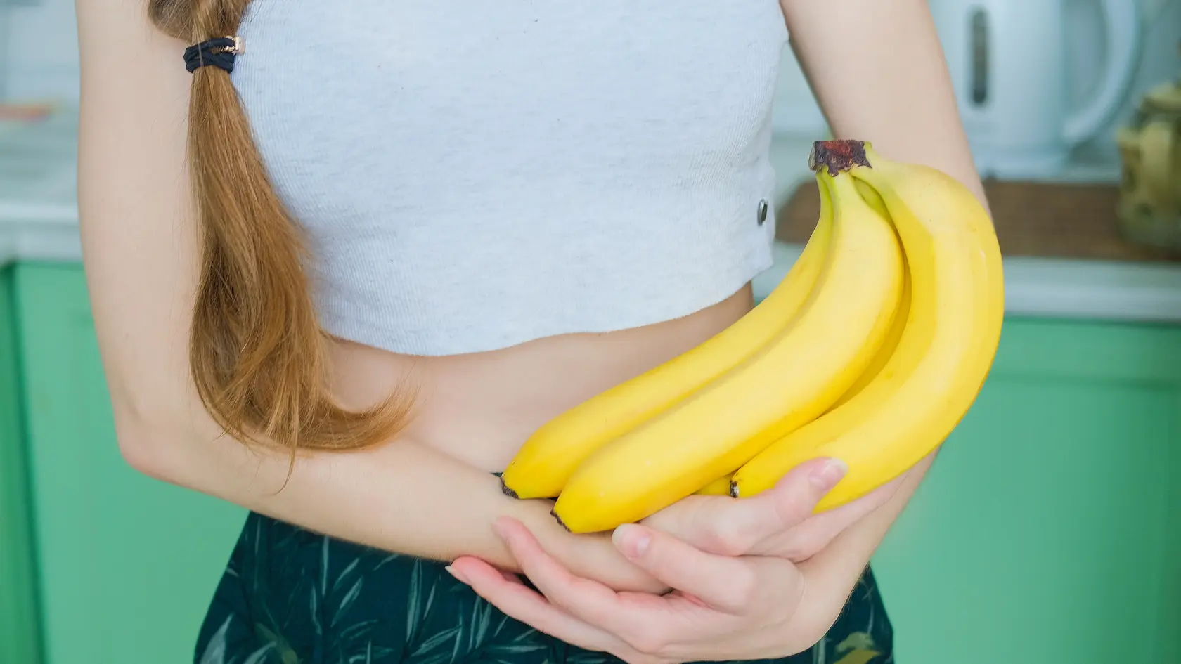 Strapec banánov v rukách ženy: Banán sa ukázal ako prospešný pre trávenie i potenciálna prevencia proti rakovine pankreasu. 