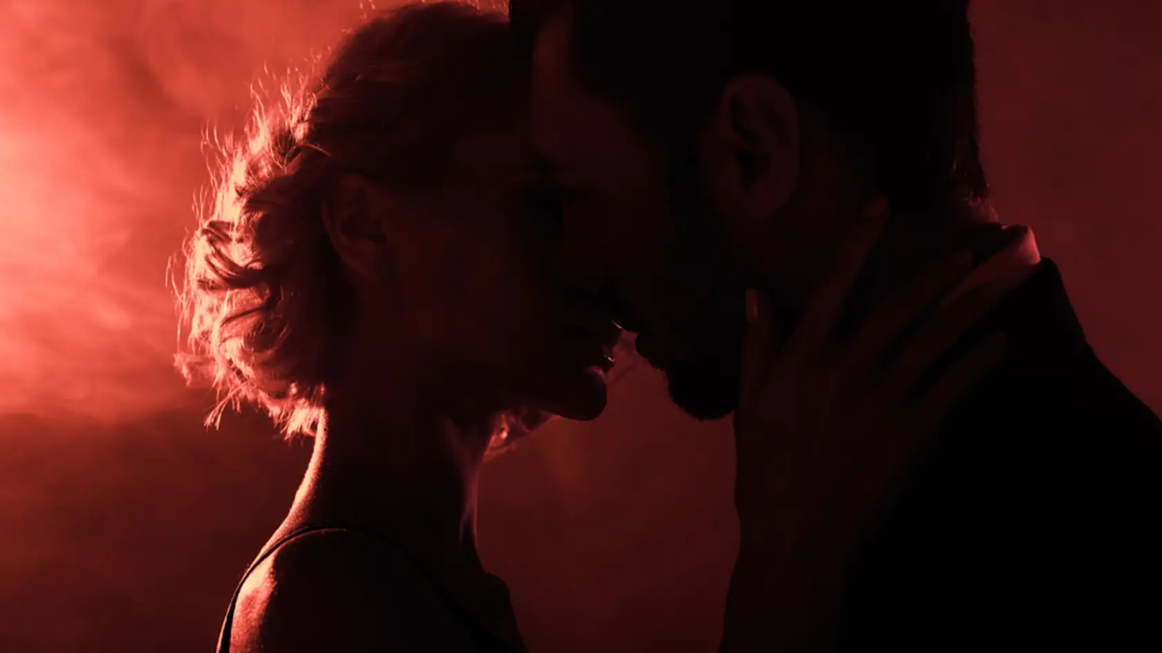 Attractive,Young,Couple,Almost,Kissing,On,Red,Smoke,Background