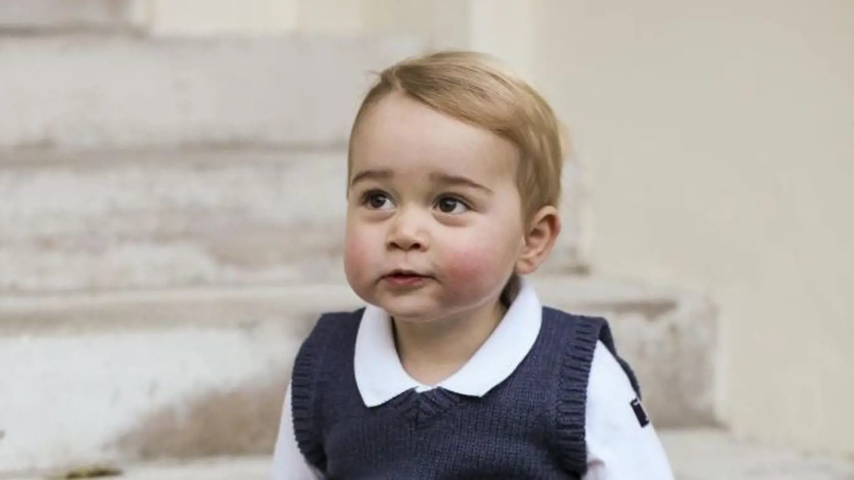 George má na sebe pletenú vestičku s motívom hradnej stráže.