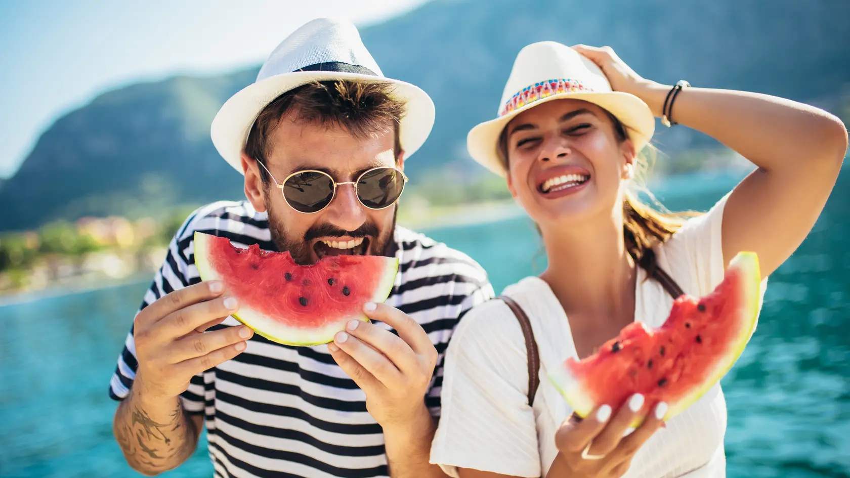 Cheerful couple holding slices of watermelon