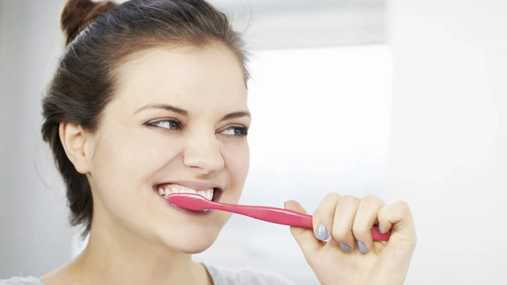 woman brushing teeth in bathroom