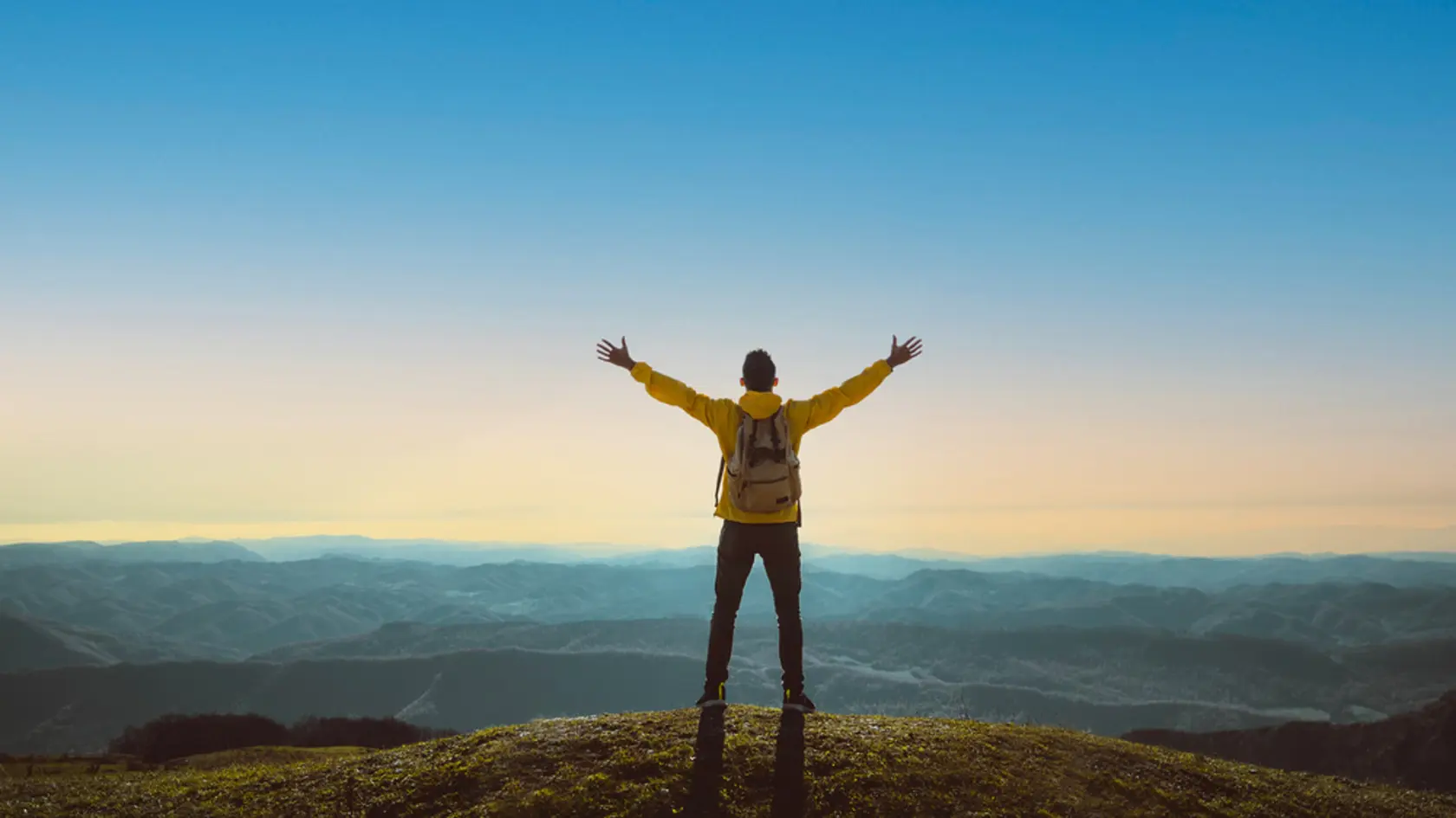 Hiker with arms up standing on the top of the mountain - Successful man enjoying triumph - Sport and success concept