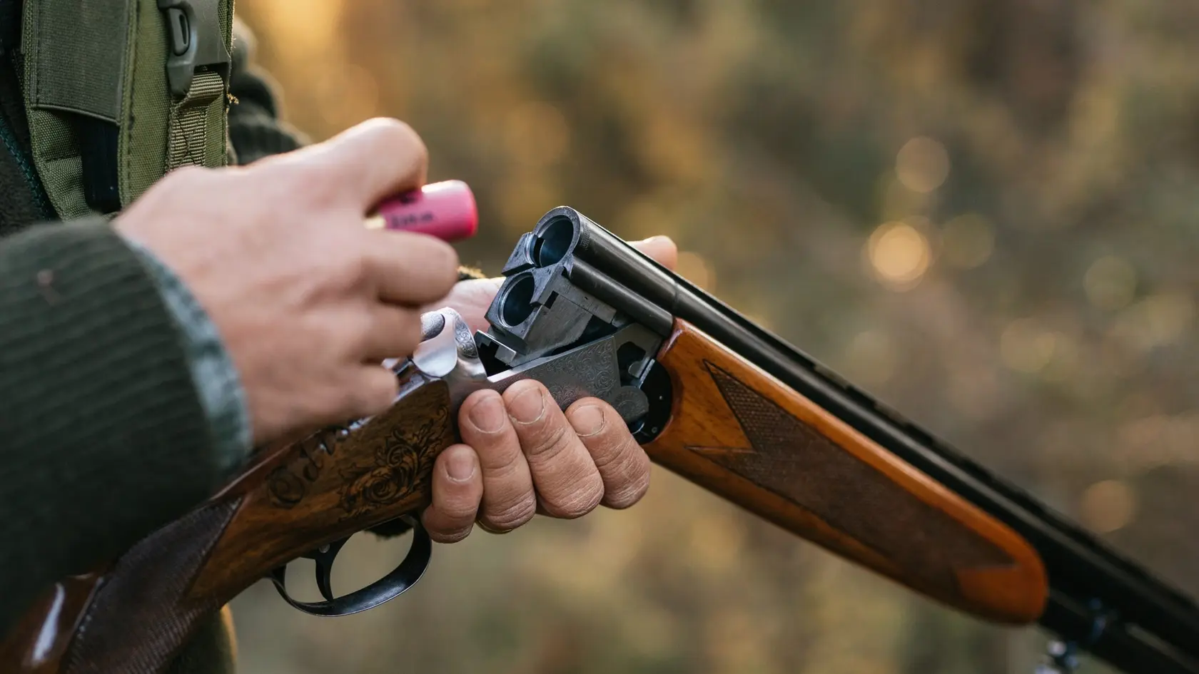 Hunter man loading his gun while hunting outdoors. Hunting season concept.