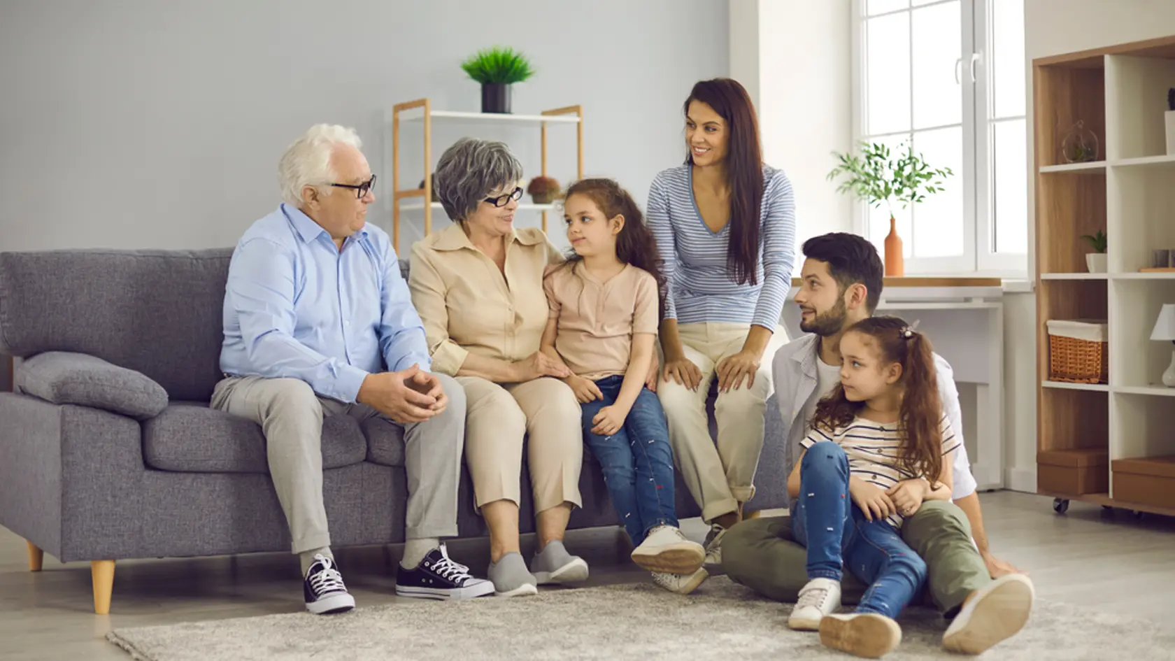 Multi-generation family sitting on sofa in living room. Portrait of a big happy family consisting of grandparents, their children and grandchildren. Family meetings and emotional communication.