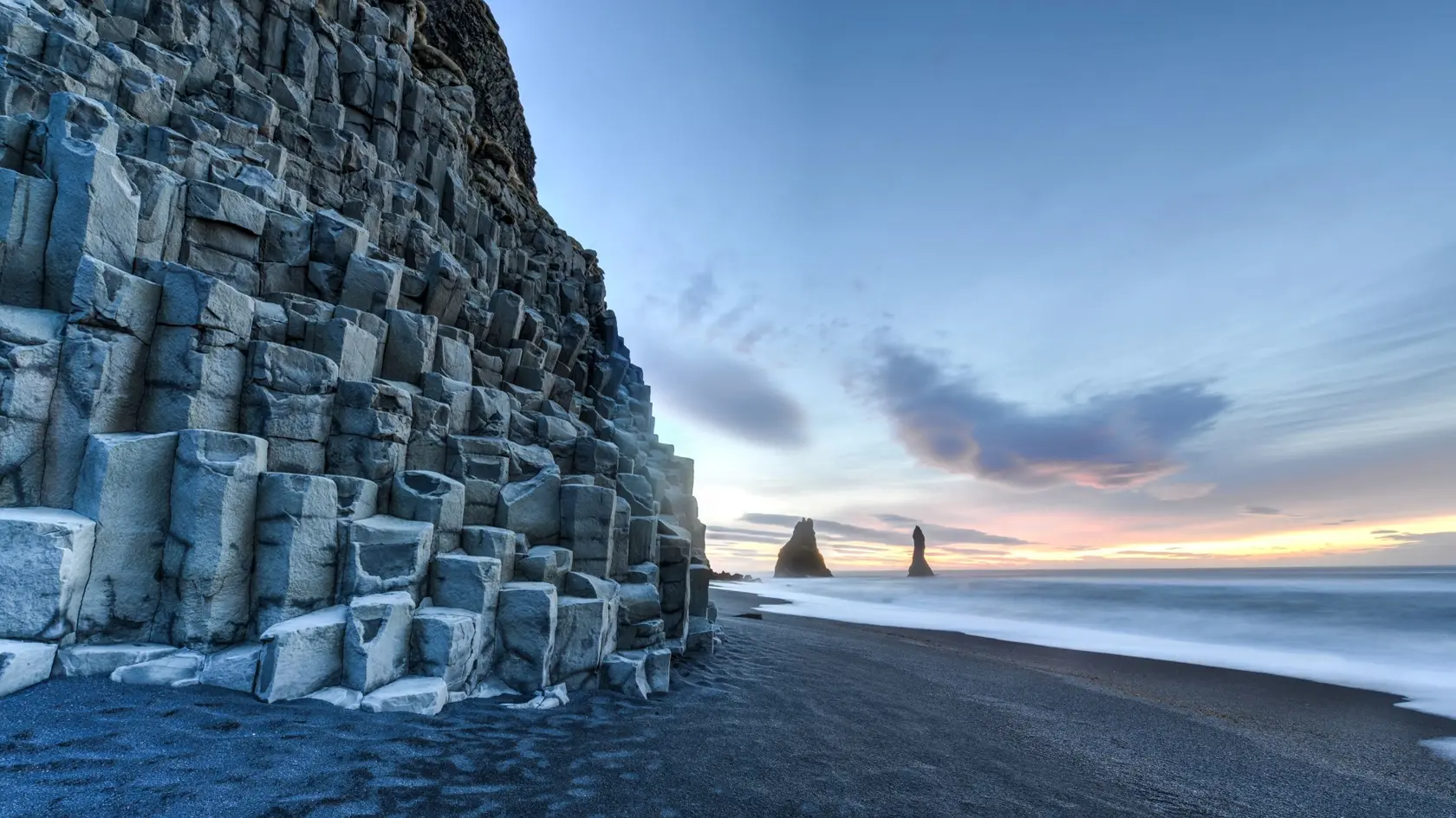 Wide view of Reynisdrangar rock formations on Reynisfjara Beach at sunrise, Halsanefhellir, Iceland.
