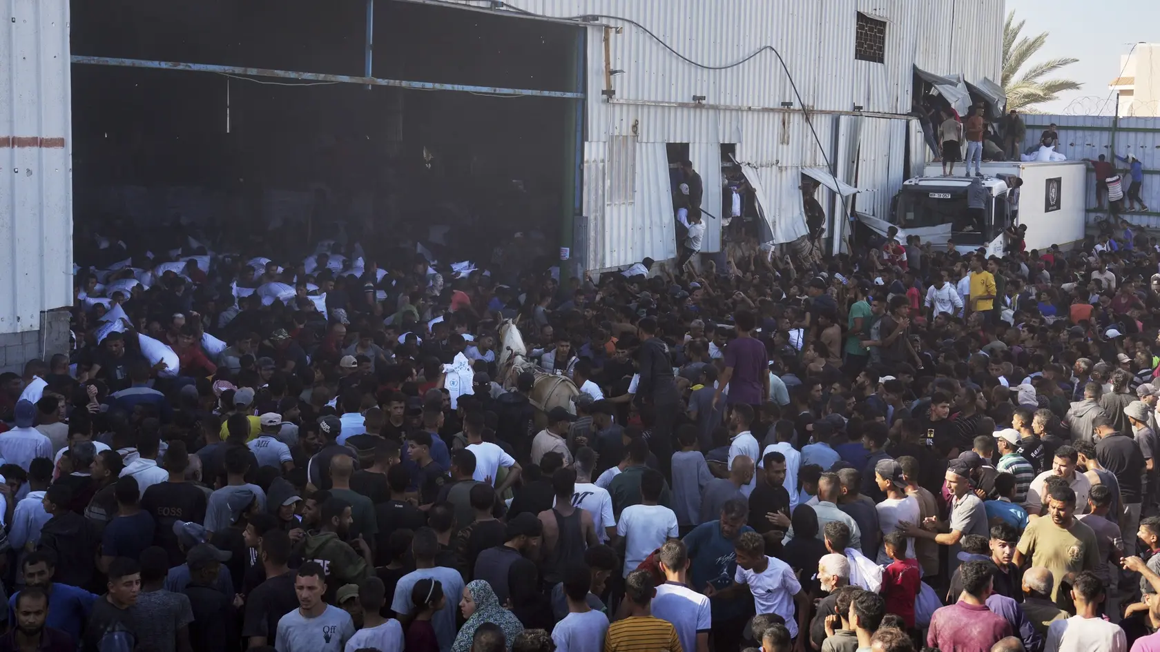 Palestínčania, ktorí vnikli do skladu OSN v meste Dajr al-Balah vo vojnou zničenom Pásme Gazy, si odnášajú vrecia s múkou v stredu 28. mája 2025.