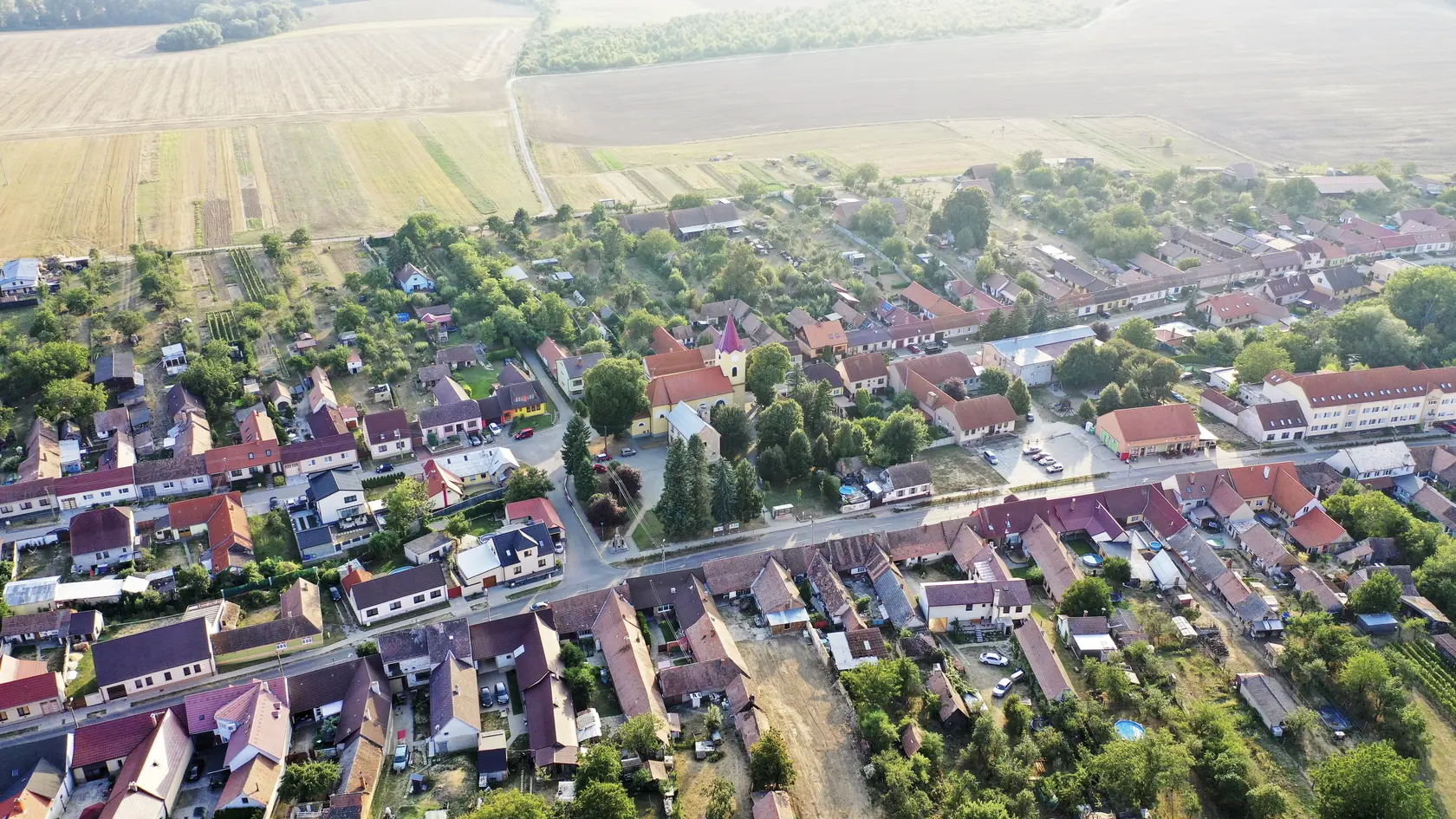 Stred obce z výšky – kostol, obecný úrad, škôlka, zariadenie pre seniorov, hasičská zbrojnica, park pri autobusovej zastávke, pohostinstvo a miestne potraviny.