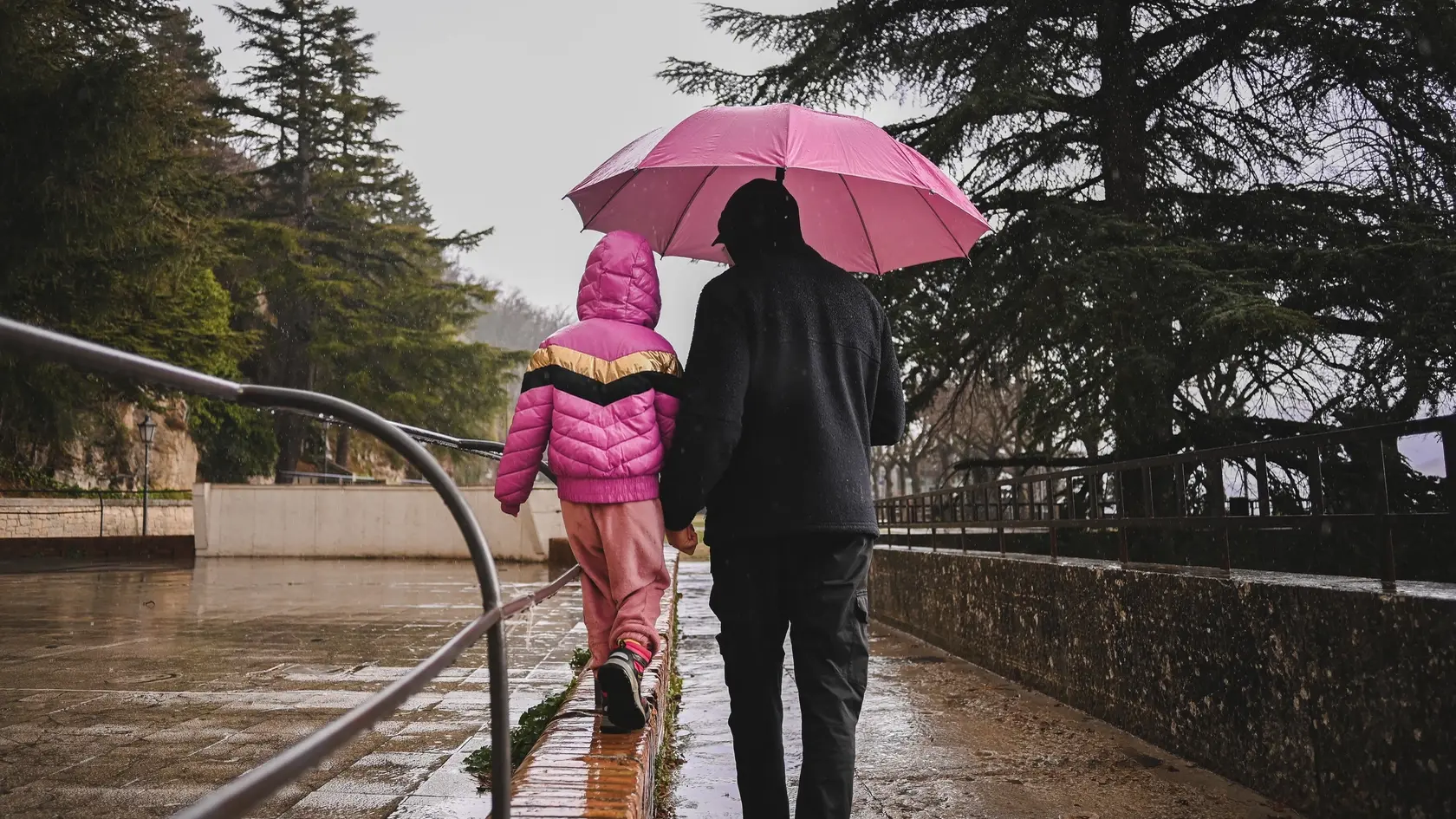 Father with daughter exploring city under the rain.