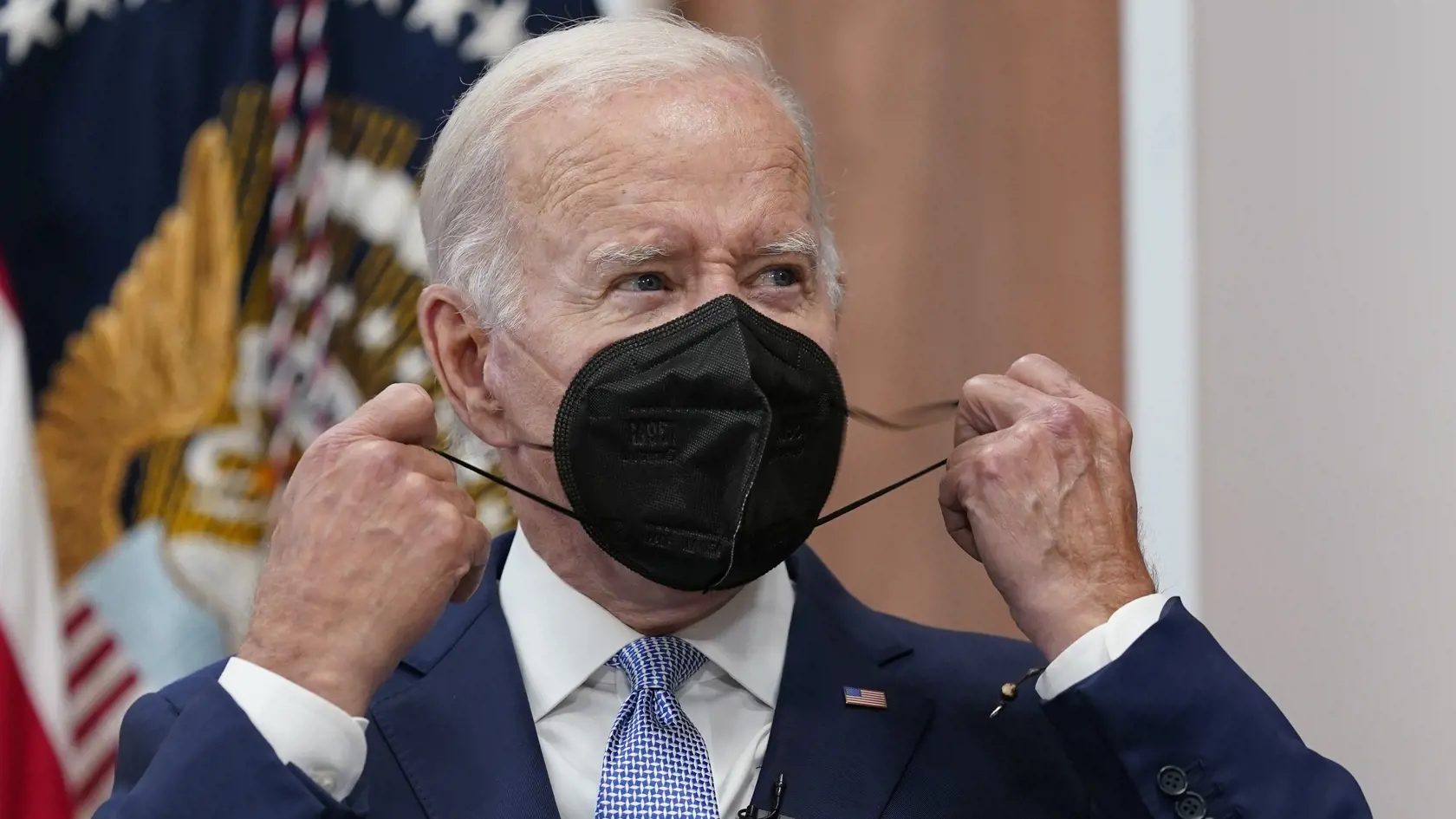 Na archívnej snímke z 28. júla 2022 americký prezident Joe Biden si dáva dole z tváre respirátor v Bielom dome vo Washingtone.