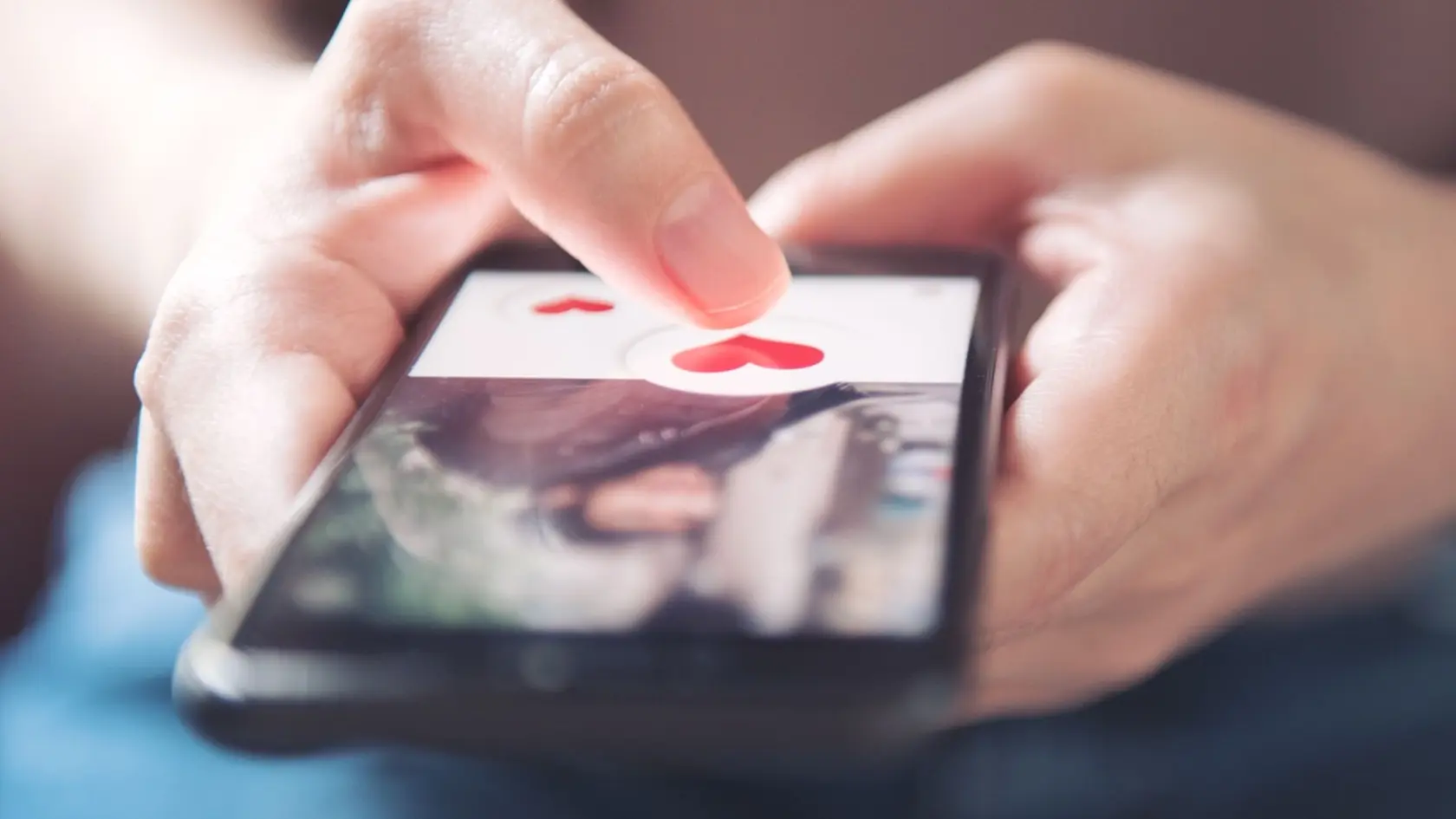 Finger of woman pushing heart icon on screen in mobile smartphone application. Online dating app, valentine's day concept.
