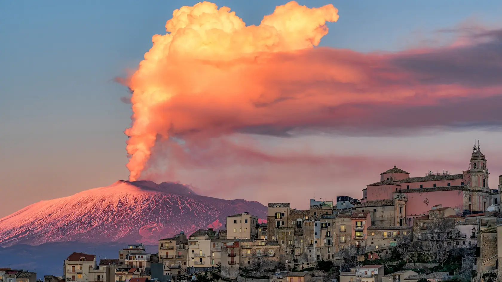 Cityscape of Centuripe and in the background the erupting Volcano Etna. Sicily. Italy. Europe. (Photo by: Antonio Treccarichi/REDA/Universal Images Group via Getty Images)