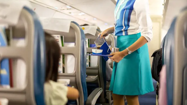 Flight,Attendant,Serving,Drinks,To,Passengers,On,Board.