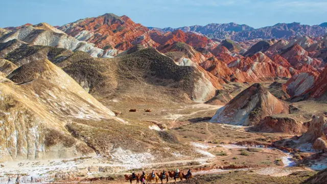 Travellers on camels in Colorful mountain in Danxia landform in Zhangye, Gansu of China. Silk road landscape, copy space for text, sunset picture