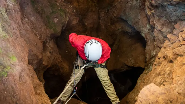 Rescuers or climber descends in a cave fast rope in the dark caves