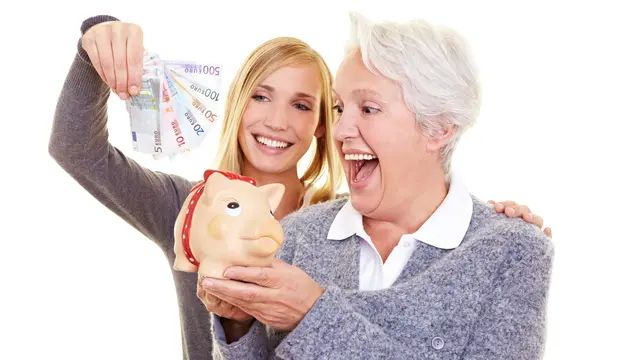 Young,And,Old,Woman,Putting,Money,In,Piggy,Bank,For