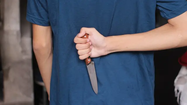 An asian boy or man holding knife in hand and hiding knife behind his back to stab his friend or enemy, angry man, kill, betray, betrayal concept, death, dead, murder, murderer, knife, stabbing,