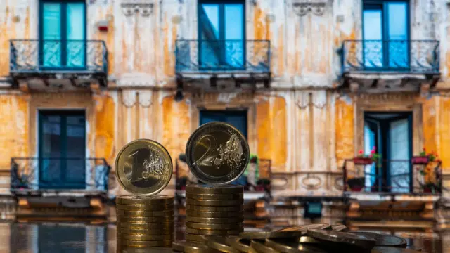 Coins in denominations of 1 and 2 euros against the background of a fragment of an old house